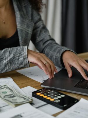 A businesswoman working on finance management with cash and calculator on desk.